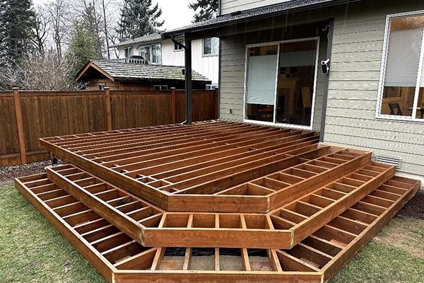 Wooden deck under construction in a backyard with multi-level steps.