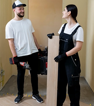 Man and woman discussing while holding construction tools and materials.