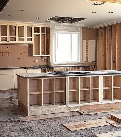 Unfinished kitchen under construction with bare walls and wooden island.