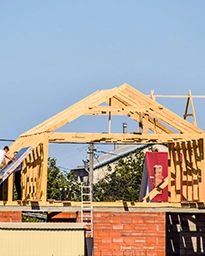 Wooden frame of a new building under construction with blue sky.