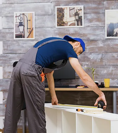 Worker measuring wooden board with tape measure in modern home office.